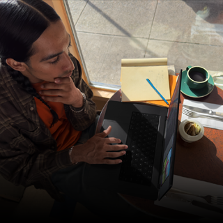Persoană care lucrează la un MacBook Pro deconectat într-o cafenea